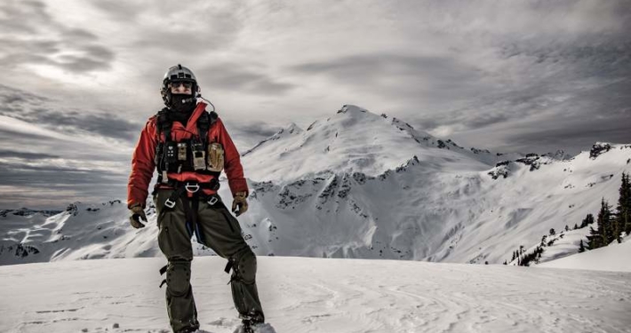 Navy pilot stands on snow covered mountain
